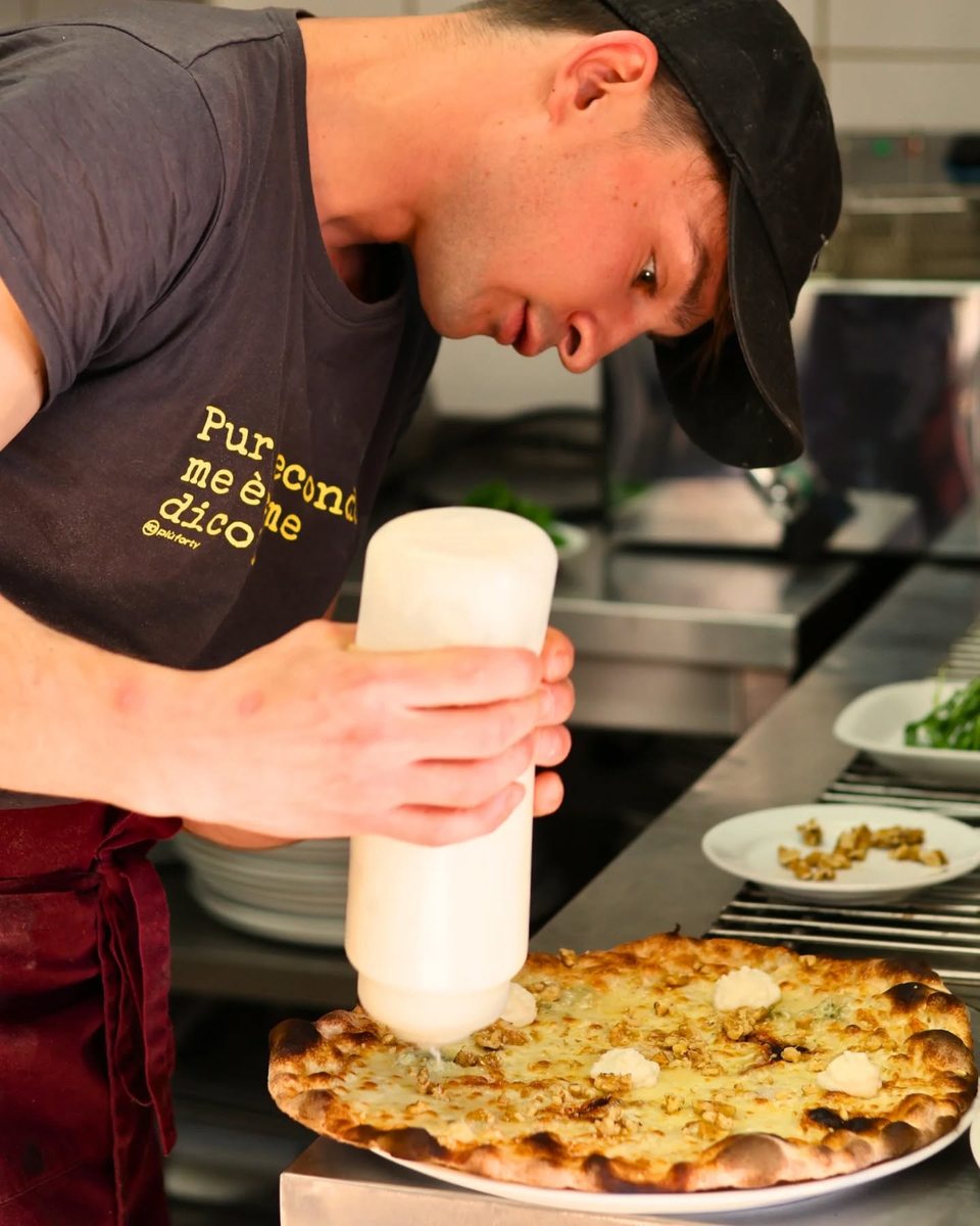 Chef preparing pizza at Pizzeria La Lupa