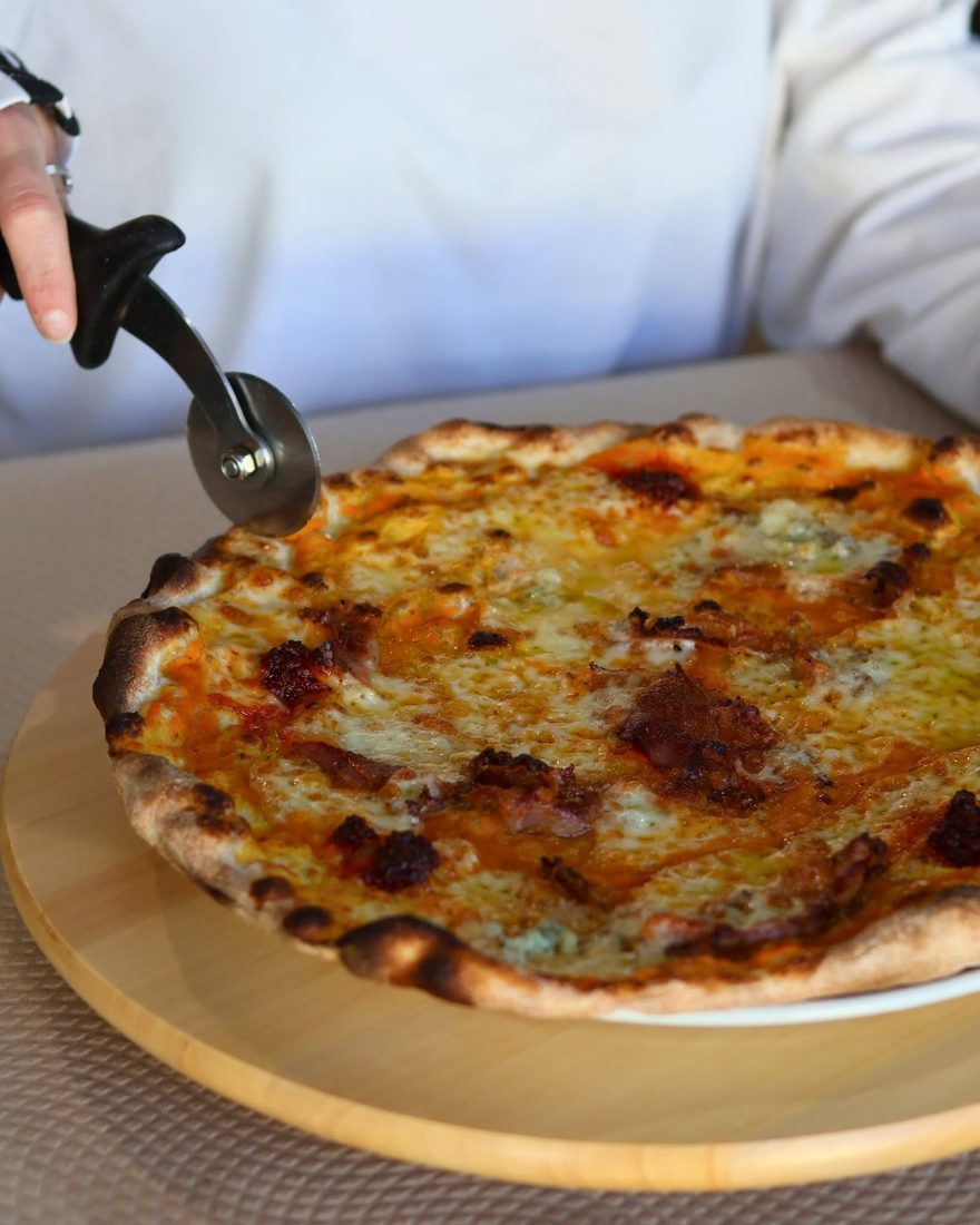 Quattro formaggi pizza being cut, Tavira